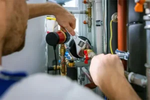 A person uses a wrench to adjust plumbing pipes in a mechanical system, ensuring the humidifier installation is perfectly integrated.